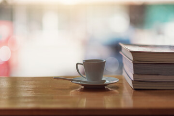 Hot coffee mug and notebook on wooden table with blurred back.