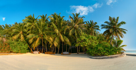 Fototapeta na wymiar Amazing wide panorama of tropical Maldives island on a sunny day. Exotic vivid beach background with blue turquoise lagoon and palm trees. Luxurious holiday and romantic honeymoon destination.