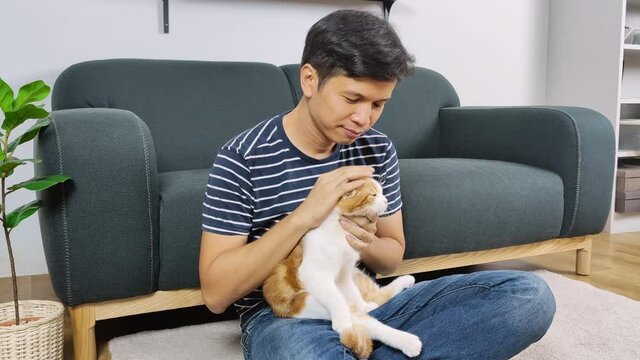 Asian man hugging and kissing a cat
