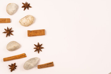 Fototapeta na wymiar White background with natural elements: stones, cinnamon sticks and anise stars