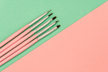 cosmetic flat lay: pink makeup brushes on green background