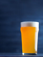 New England IPA beer glass on dark blue wooden background