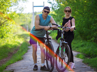 Fototapeta na wymiar Young couple man and woman on a summer bike ride in the park