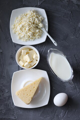 An assortment of dairy products on a wooden table in the morning for breakfast - milk, cheese, egg, yogurt, sour cream, cottage cheese and butter.