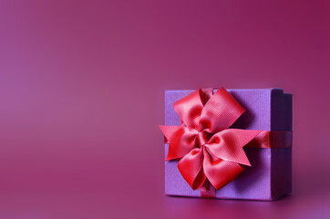 Holiday concept banner with hand made gift box, bow on a purple background with space for text.
