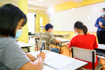 Asian female teacher and student Wearing a mask to prevent coronavirus (COVID 19) teaching elementary school students in a rural school on the first day of the semester.