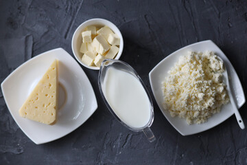An assortment of dairy products on a wooden table in the morning for breakfast - milk, cheese, egg, yogurt, sour cream, cottage cheese and butter.