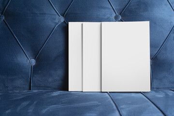Books with blank cover on a blue velvet sofa, editable mock-up series ready for design