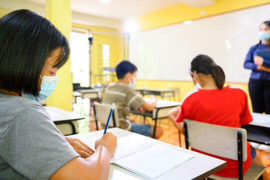 Asian Female Teacher And Student Wearing A Mask To Prevent Coronavirus (COVID 19) Teaching Elementary School Students In A Rural School On The First Day Of The Semester.