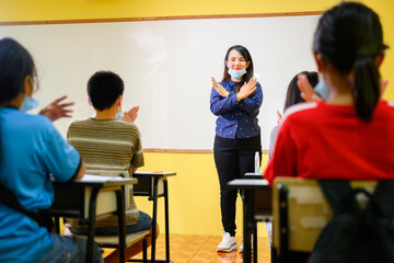 Asian female teacher and student Wear a mask to prevent coronavirus (COVID 19) teaching elementary school students in a rural school and teach them how to wear masks correctly.