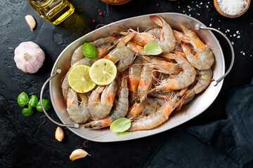 Fresh raw shrimp marinated with spices and lime juice, ready to roast. Black background. Top view