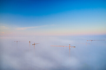 View of tower cranes at dawn during heavy fog. Concept of urban construction of new houses and districts