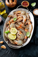 Fresh raw shrimp marinated with spices and lime juice, ready to roast. Black background.