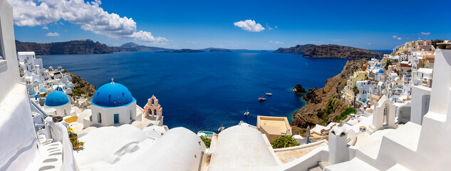 Panoramic view to the beautiful three blue dome church at the village of Oia, Santorini, Greece,...