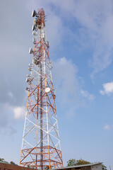 the tower of mobile operators. red and white metal structure, against a cloudy sky