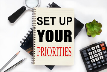 set up your priorities. an open notebook lies on a closed notebook near a calculator and a...