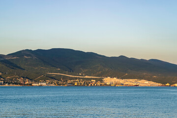 Factory on the seashore at the foot of the mountain. Loading port on the seashore at the foot of the mountain. View from the opposite bank.