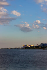Naklejka premium Coastline of a modern coastal town at sunset. Church and high-rise residential buildings on the seashore. Vertical orientation. Portrait orientation.