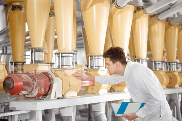 Worker operator checks mill production line of cereals, flour, millet and seeds. Food industry...