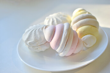 Colorful delicious marshmallows on a white plate