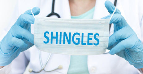 Word shingles on a medical mask in the hands of a doctor. Preventive Medicine