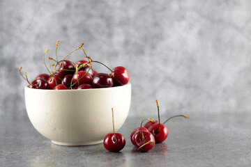 healhy eating concept - white bowl of black cherry isolated on gray background