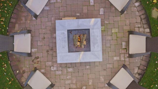 Overhead aerial over a back yard fire pit with wicker chairs. spin zoom out aerial.
