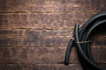 Old rubber water hose on the brown wooden floor background with copy space.