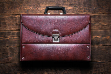 Retro style briefcase on the wooden desk table flat lay background.