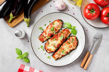 Baked eggplant with mozzarella cheese, chopped tomatoes and fresh basil leaves. Vegetarian food recipe. Light gray background, top view. 