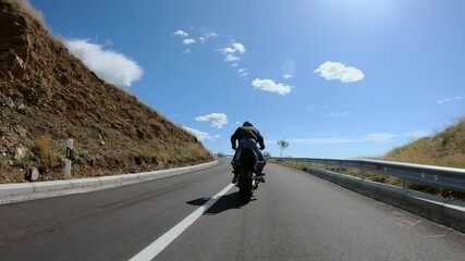 Stunt biker man riding fast sport motorbike on mountain road burning tire
