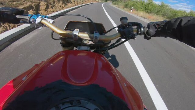 Biker stunt ride biike on mountain rural road and do wheelie on motorcycle, pov