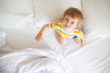 Top view of cheerful little boy in white bed early in the morning. Portrait of a handsome boy...
