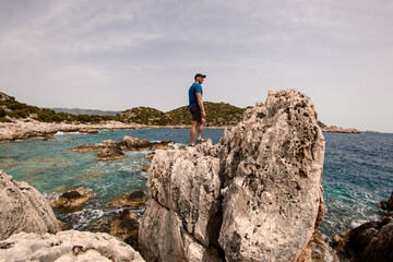 man stands on large stone on the seashore against the backdrop of landscape