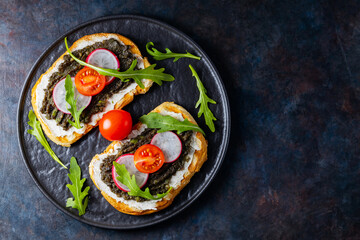 Healthy food. Avocado toasts with avocado, cream cheese and radish. Toasts with avocado, arugula and cherry tomatoes on a dark background. Copy space. Top view