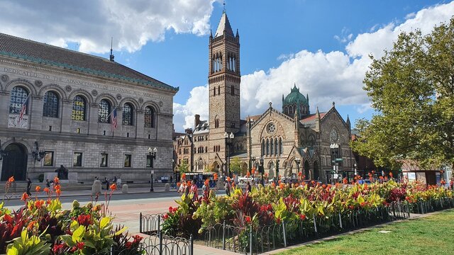 Old church in a street with flowers, trees, sky and historic buildings