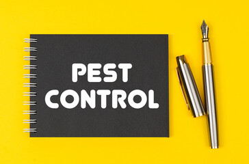 On a yellow background lies a pen and a black notebook with the inscription - Pest Control