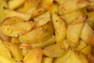Fresh spiced potatoes baked in pieces. Vegetarian dish. Fried potato slices, close up. Potato dish.