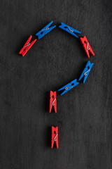Clothespins in the form of question mark on black background. Question mark made from colorful clothespins