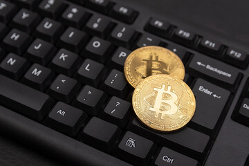 Gold Bitcoins on computer keyboard close up. Electronic virtual money and mining cryptocurrency concept.