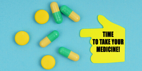 On a blue background, there are pills and a hand-sticker with the inscription - Time to take your medicine