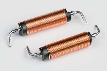 Two solenoids with helical copper wire wound on black coil on white background. Close-up of electronic components with magnetic field inside. Long cylindric inductors with ferrite core. Electromagnet. - obrazy, fototapety, plakaty