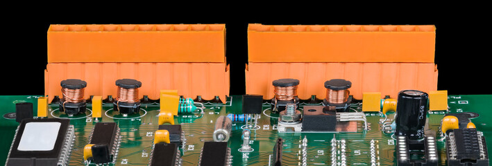 Panoramic detail of electronic components on green circuit board on a black background. Close-up of...