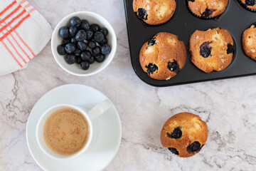 Top view of a marble table on which is a batch of muffins with a cup of coffee.