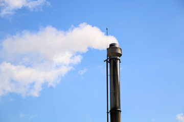 Steam chimney of dairy factory against blue sky. factory chimney