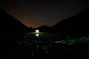 amazing view of the night starry sky among mountains and lantern by the lake