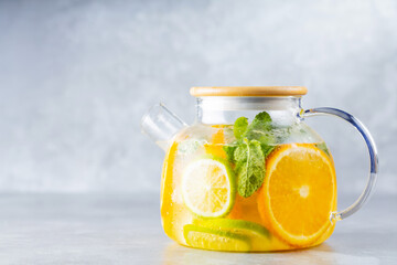 Detox lemonade drink of water, lemon, orange and mint leaves in a transparent teapot. Lime mint...