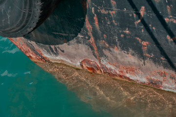 A rusty old ship with corrosion is in the water