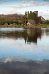 Fototapeta premium Ruins of Menlo castle covered with ivy on river Corrib, Galway city, Ireland. Building reflection in water. Nobody. Historical landmark.