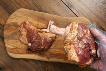 Two fresh uncooked duck legs on a wooden cutting board and wooden table. Poultry product.